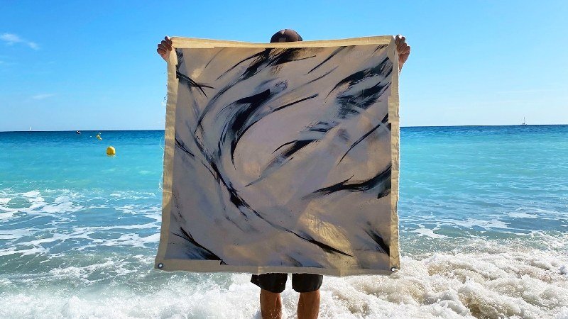 sheOne on the beach holding his artwork